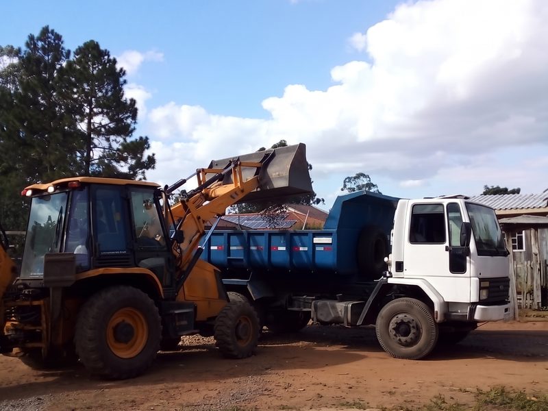 Retroescavadeira carregando caminhão caçamba com material de obra